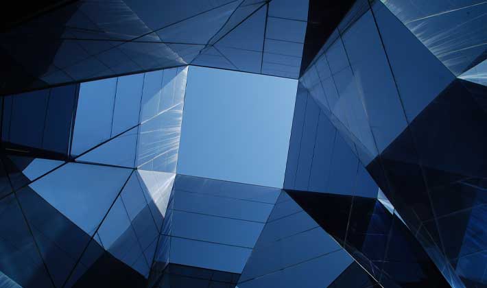 Fotografia de edifício espelhado refletindo o céu azul